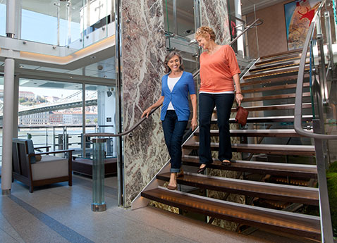 Two women walking down the stairs of the Atrium of a Viking river ship